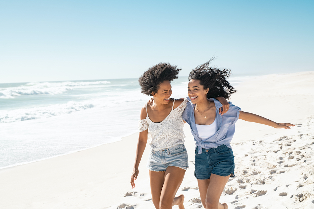 Two women laughing on a beach while practicing summer skin care in LaSalle