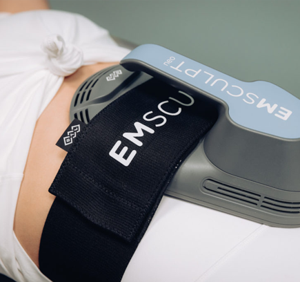 A close-up of an EMSculpt device attached to a person's abdomen.