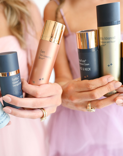 Two women holding various skincare products in their hands, showcasing different serums and creams.